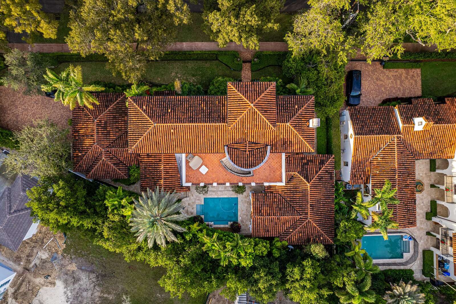 Aerial view of a tile-roofed Florida home with a pool and mature landscaping
