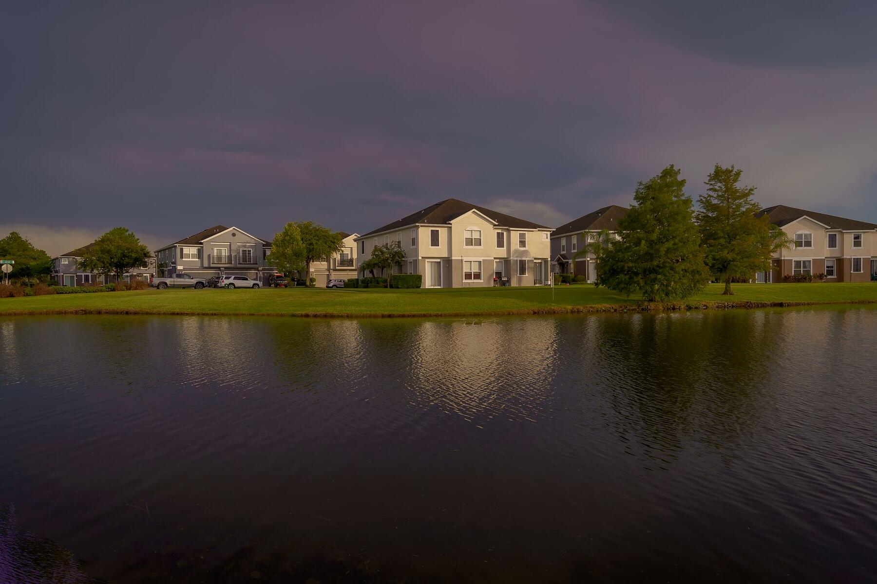 Houses along a lake at dusk under a darkening sky