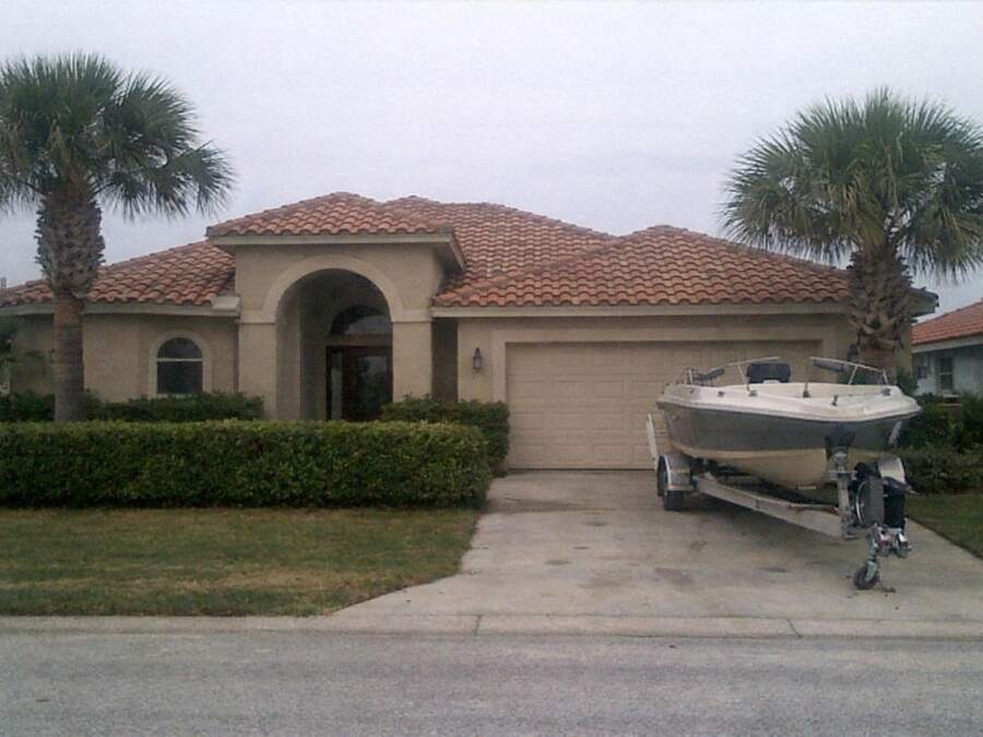 A Mediterranean-style house with a barrel tile roof and palms