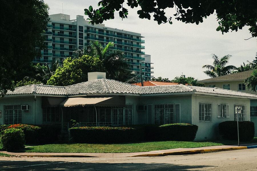 A mid-century single-story house beneath mature trees