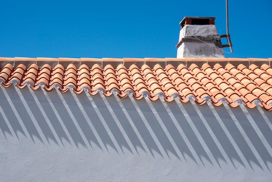 The ridge line of a barrel tile roof with a vent stack