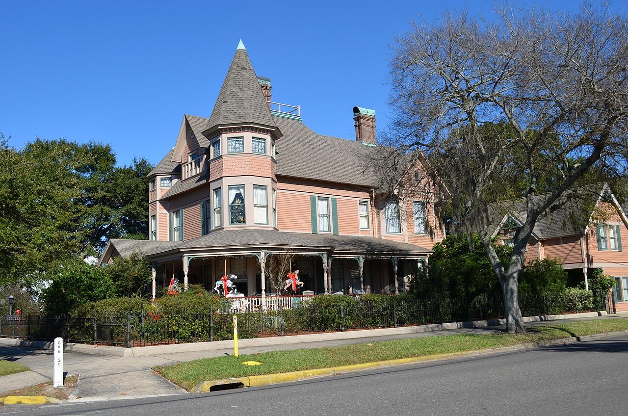A restored two-story Victorian house with a wraparound porch