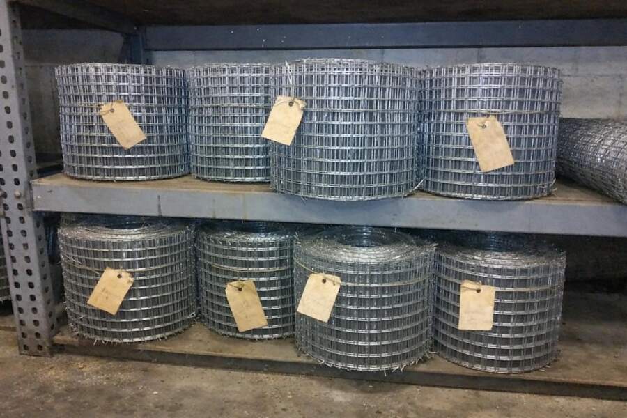 Rolls of galvanized welded wire mesh stacked in a warehouse